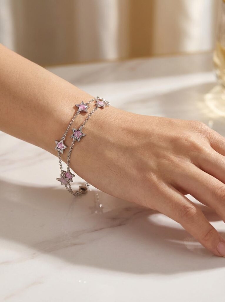 Bracelet étoile rose argenté pailleté Lueur Rosée porté sur un poignet féminin avec chaîne fine