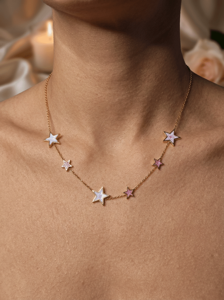 Collier étoile rose pailleté doré Aura Céleste porté sur un cou féminin avec chaîne fine