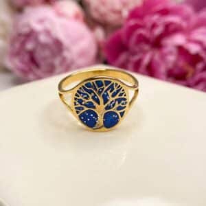 Bague Arbre de Lumière bleue pailletée Racine Céleste finition dorée posée sur table