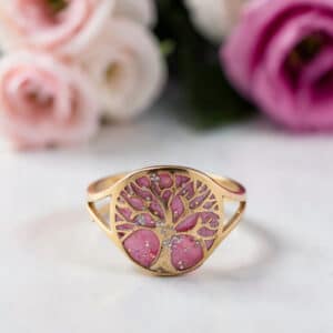 Bague Arbre de Lumière rose pailletée Floraison de Vie finition dorée posée sur table