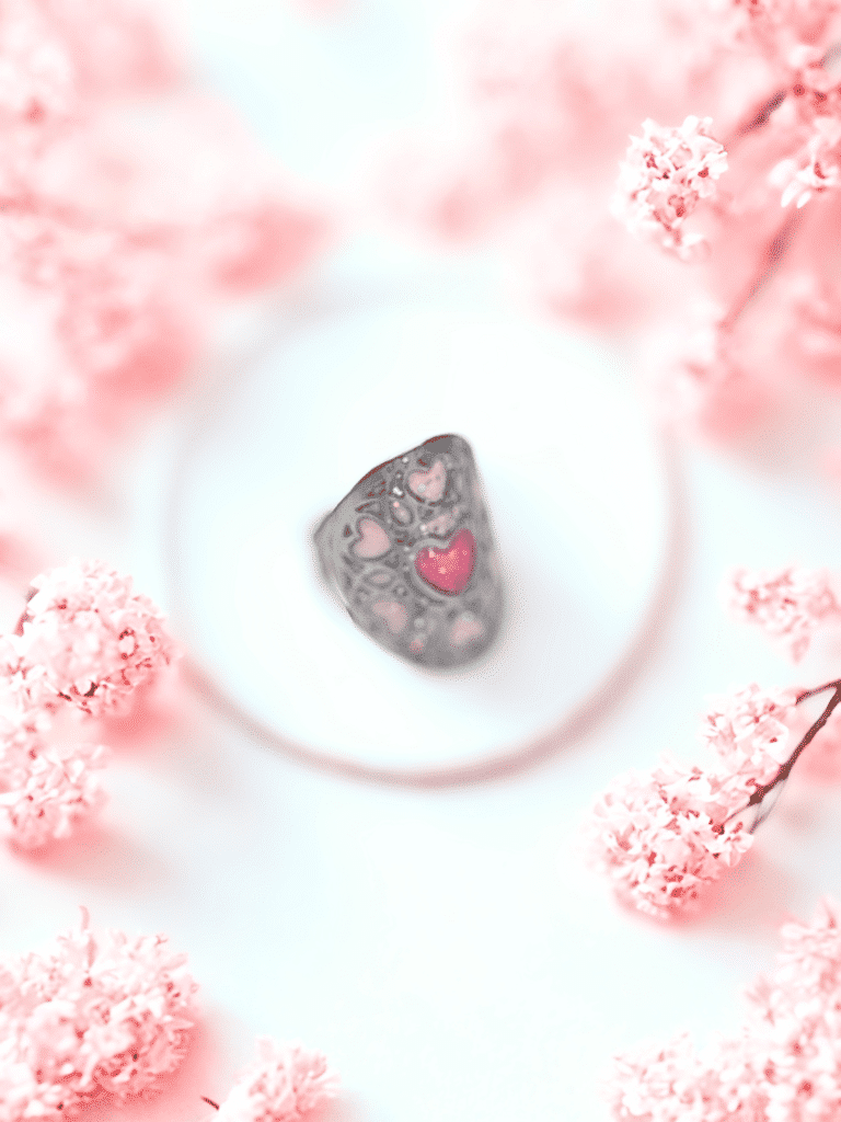 Bague Cœur en Lumière rose pailletée Cœur Enchanteur finition argentée posée sur table