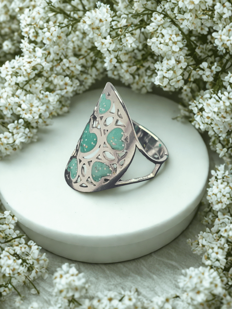 Bague Cœur en Lumière verte pailletée Cœur Florissant finition argentée posée sur table