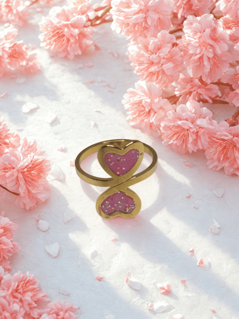 Bague duo Cœur en Lumière rose pailletée Double Tendresse finition dorée posée sur table