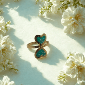 Bague duo Cœur en Lumière verte pailletée Double Nature finition dorée posée sur table