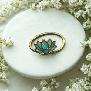 Bague Lotus Sacré vert pailletée Lotus Émeraude finition dorée posée sur table