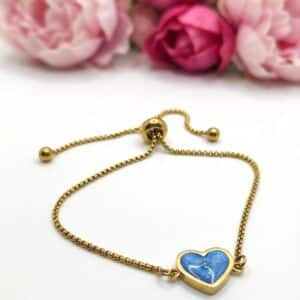 Bracelet Cœur en Lumière bleu pailleté Lueur du Cœur finition dorée posé sur table