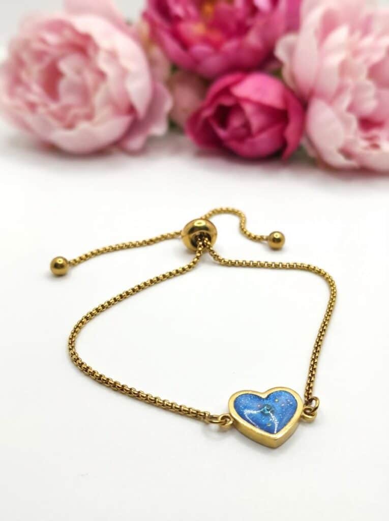 Bracelet Cœur en Lumière bleu pailleté Lueur du Cœur finition dorée posé sur table