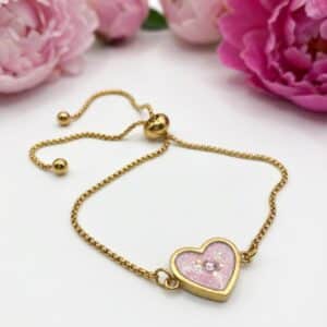 Bracelet Cœur en Lumière rose pailleté Douceur du Cœur finition dorée posé sur table