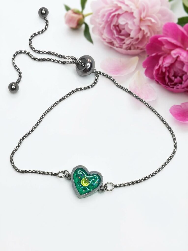 Bracelet Cœur en Lumière vert pailleté Éclat du Cœur finition argentée posé sur table