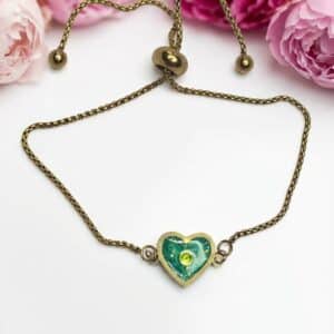 Bracelet Cœur en Lumière vert pailleté Éclat du Cœur finition dorée posé sur table