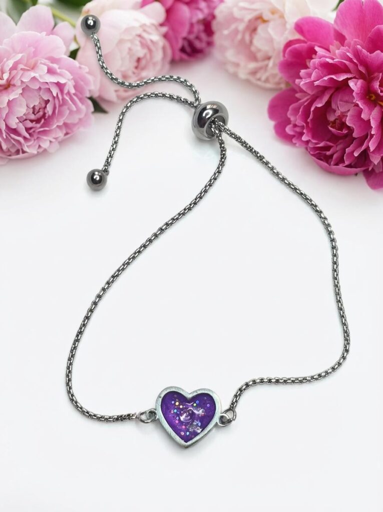 Bracelet Cœur en Lumière violet pailleté Mystère du Cœur finition argentée posé sur table