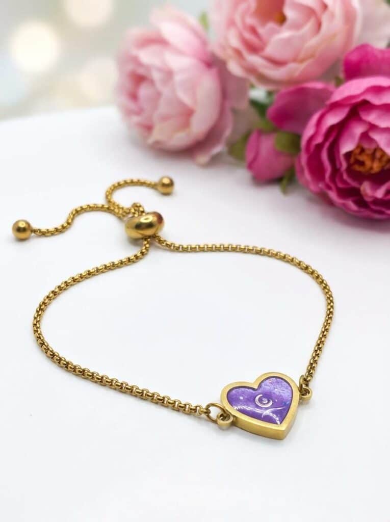 Bracelet Cœur en Lumière violet pailleté Mystère du Cœur finition dorée posé sur table
