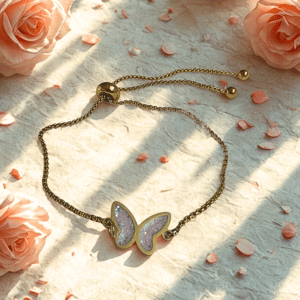 Bracelet Papillon Éternel rose pailleté Envol Délicat finition dorée posé sur table