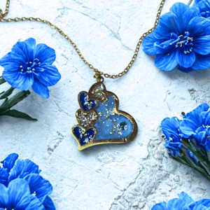 Collier Cœur en Lumière bleu pailleté Cœur Céleste finition dorée posé sur table