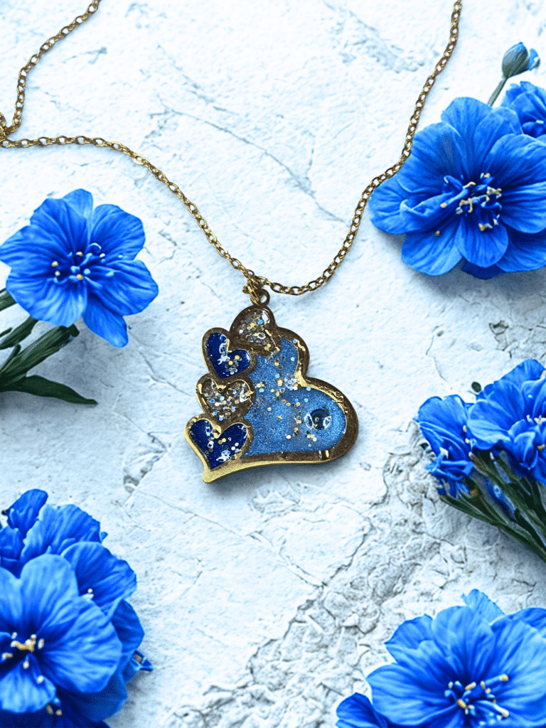 Collier Cœur en Lumière bleu pailleté Cœur Céleste finition dorée posé sur table