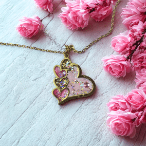 Collier Cœur en Lumière rose pailleté Cœur Tendre finition dorée posé sur table