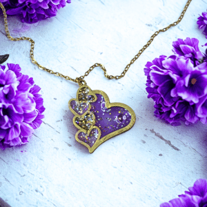 Collier Cœur en Lumière violet pailleté Cœur Mystique finition dorée posé sur table