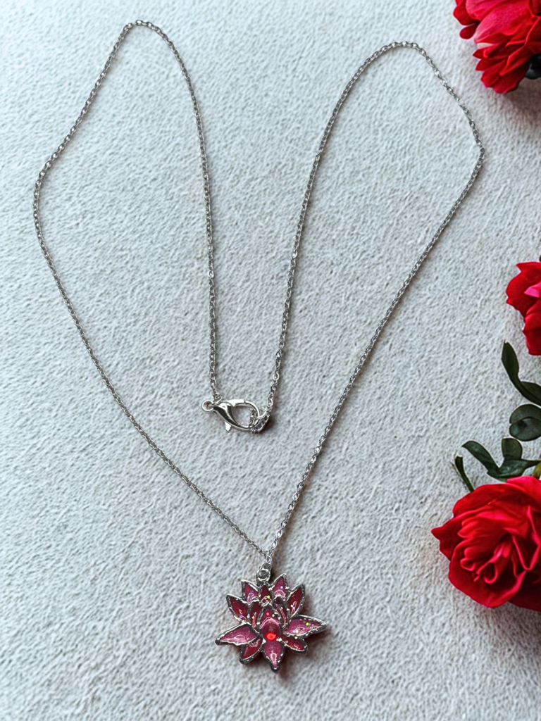 Collier Lotus Sacré rouge pailleté Flamme du Lotus finition argentée posé sur table