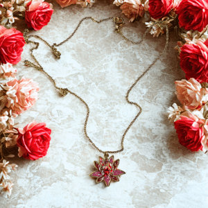 Collier Lotus Sacré rouge pailleté Flamme du Lotus finition dorée posé sur table