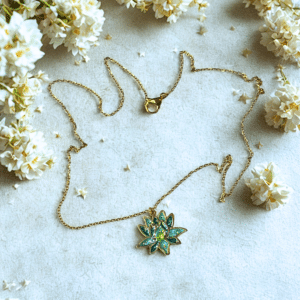 Collier Lotus Sacré vert pailleté Éveil Émeraude finition dorée posé sur table