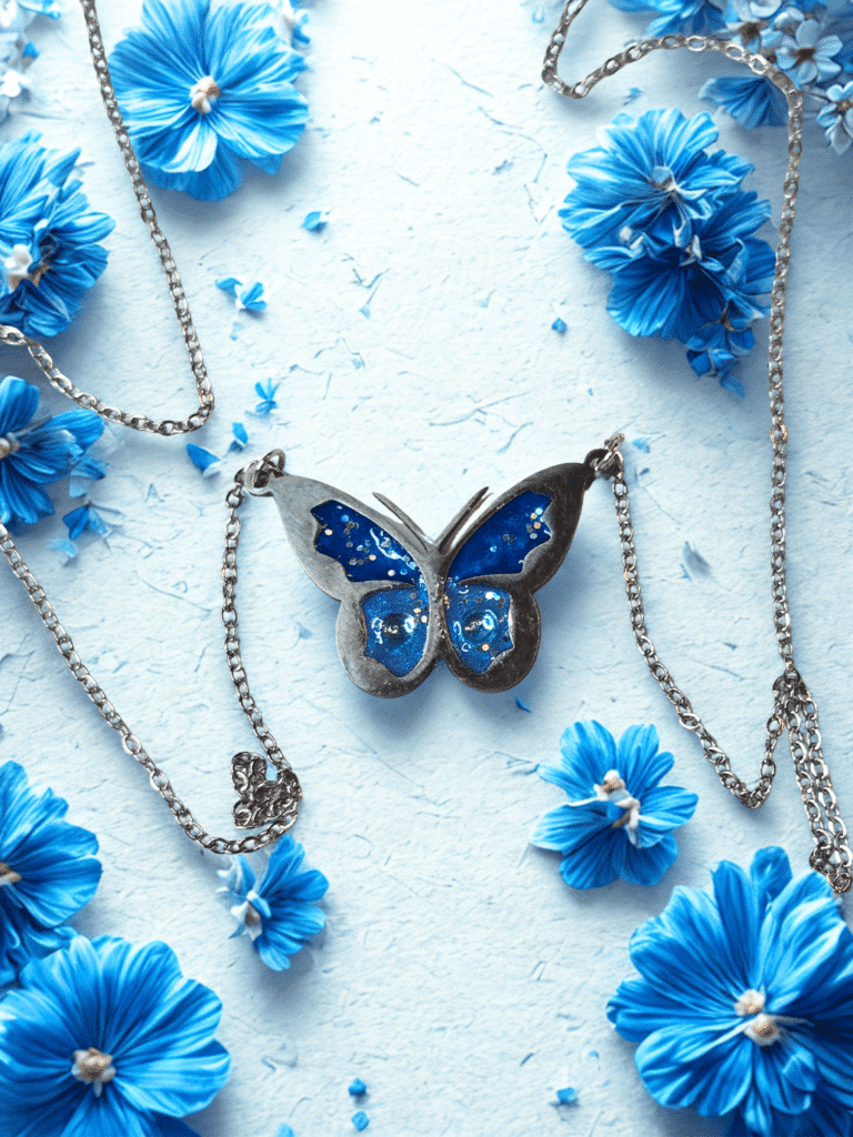 Collier Papillon Éternel bleu pailleté Aile Céleste finition argentée posé sur table