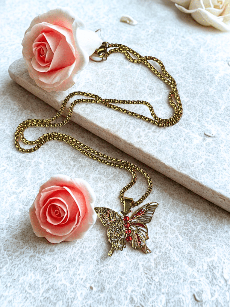 Collier Papillon Éternel doré Ailes de Feu posé sur support pierre avec roses
