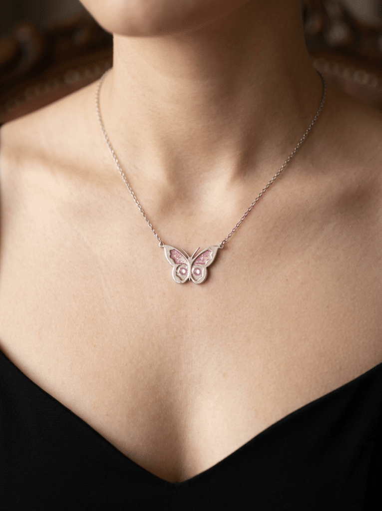 Collier Papillon Éternel rose pailleté Aile Enchantée finition argentée porté au cou