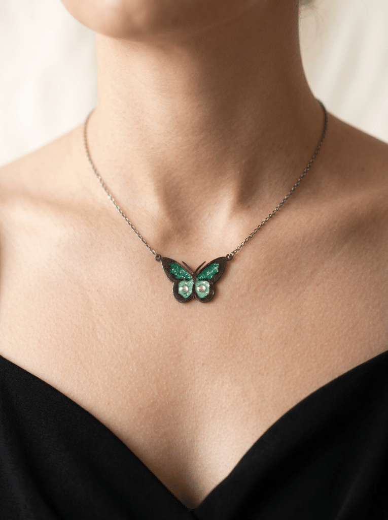 Collier Papillon Éternel vert pailleté Aile Émeraude finition argentée porté au cou